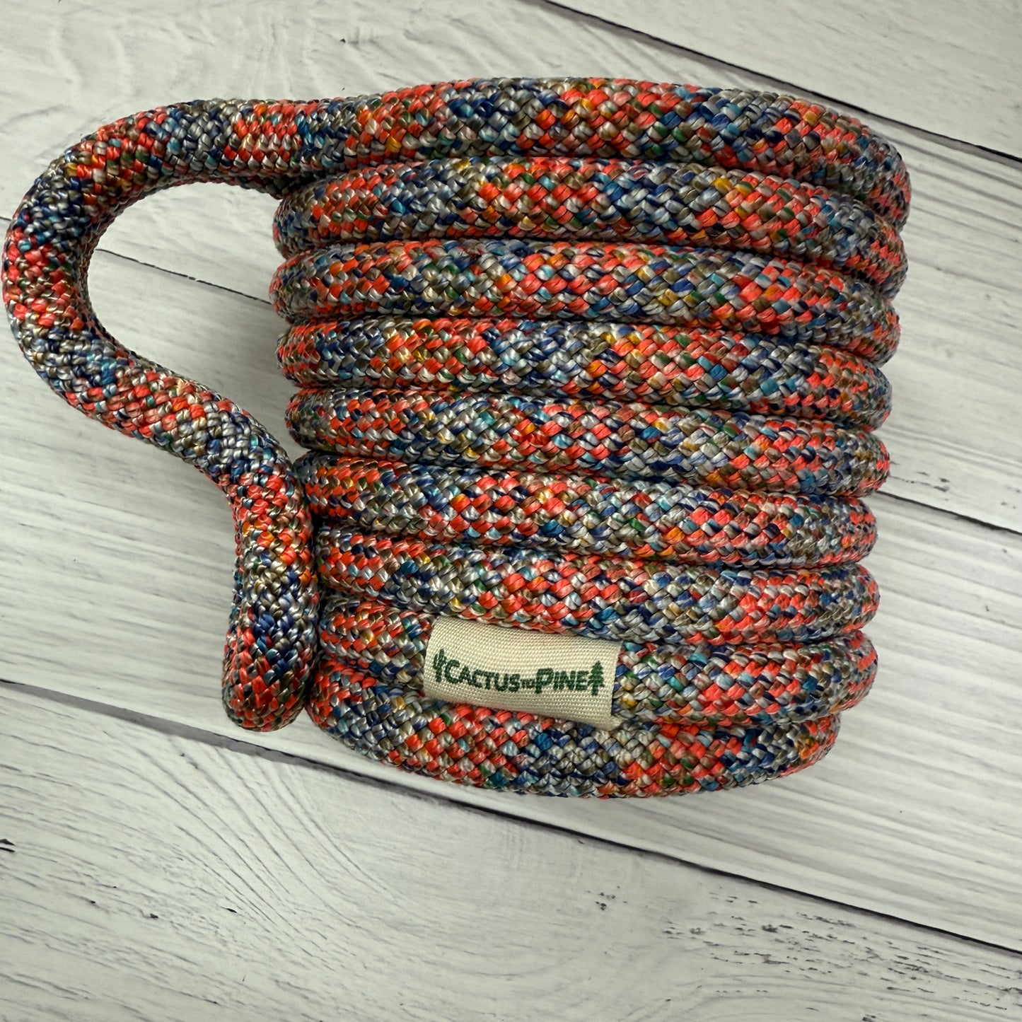 A coiled rope with a label that reads "Cactus Pine" is placed on a white wooden surface.