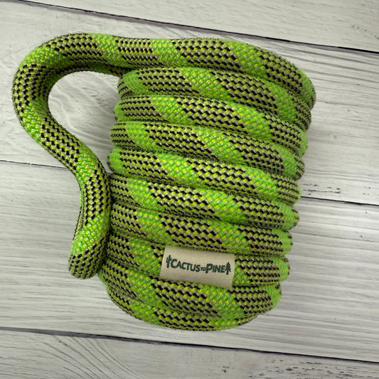 A coiled green and black rope with a label that reads "Cactus Pine" is placed on a white wooden surface.