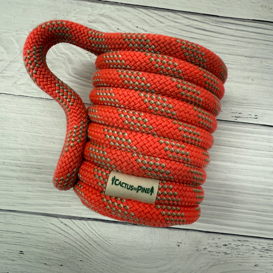 A coiled orange rope with a green label that says 'Cactus Pine' on a white wooden surface.