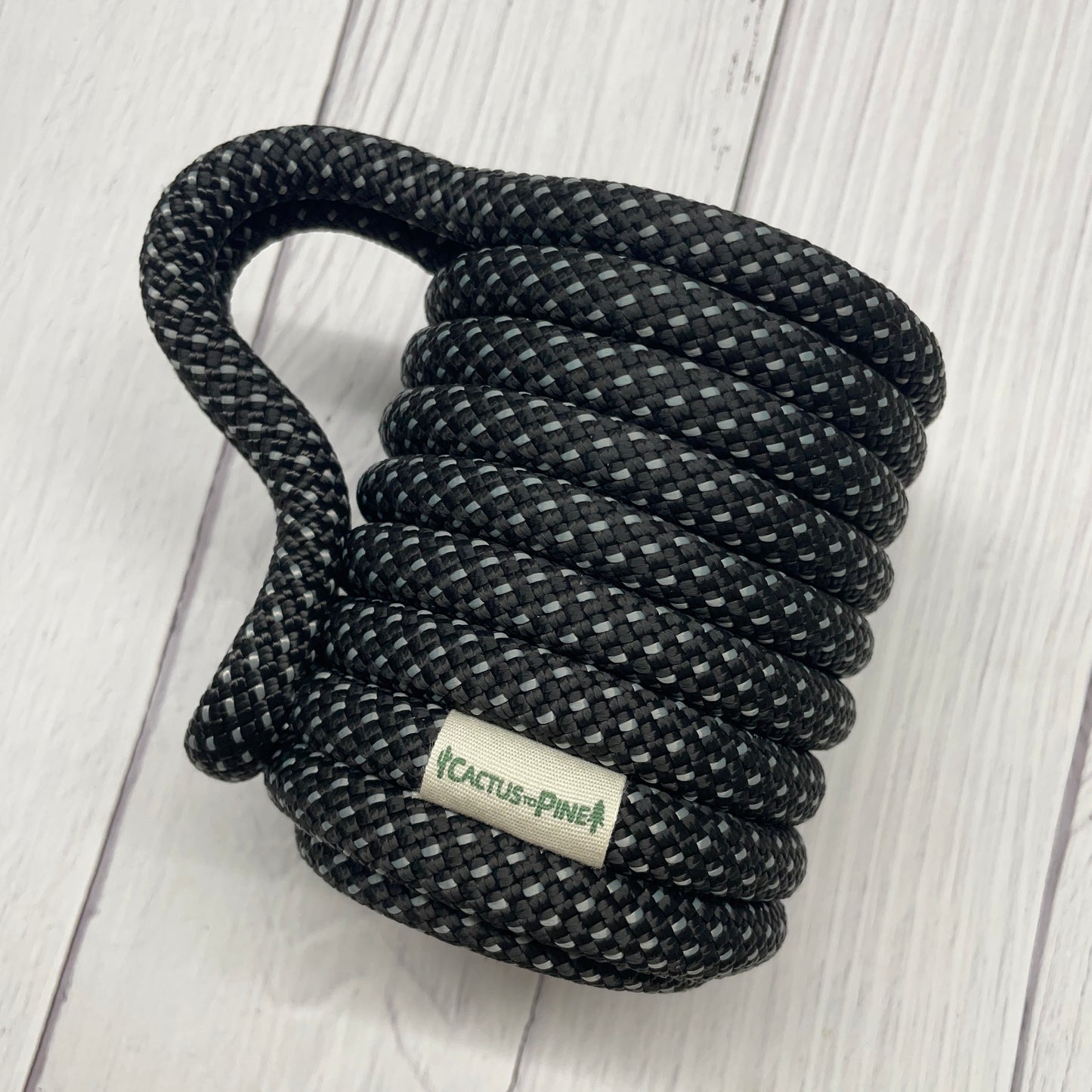 A black and gray rope coiled on a white wooden surface.