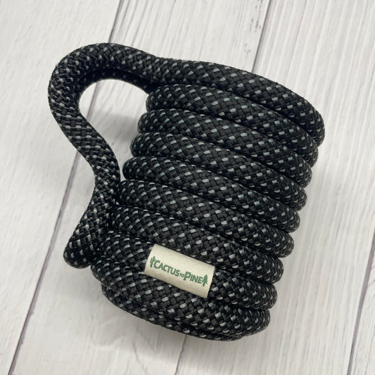 A black and gray rope coiled on a white wooden surface.