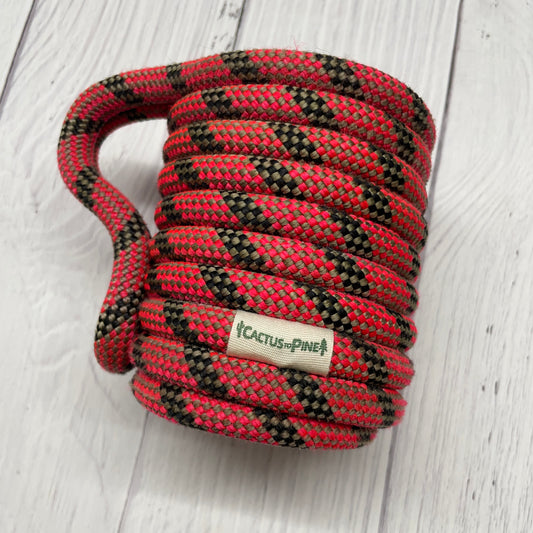 A coiled red and black rope with a label that reads "Cactus Pine" is shown on a white wooden surface.