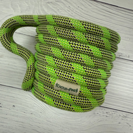 A coiled green and black rope with a label that reads "Cactus Pine" is placed on a white wooden surface.