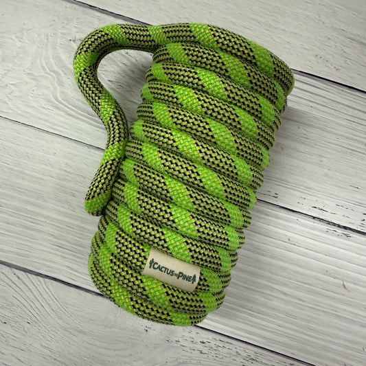 A coiled green and black rope is resting on a white wooden surface.